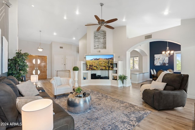 living room featuring high vaulted ceiling, light wood-type flooring, and ceiling fan with notable chandelier