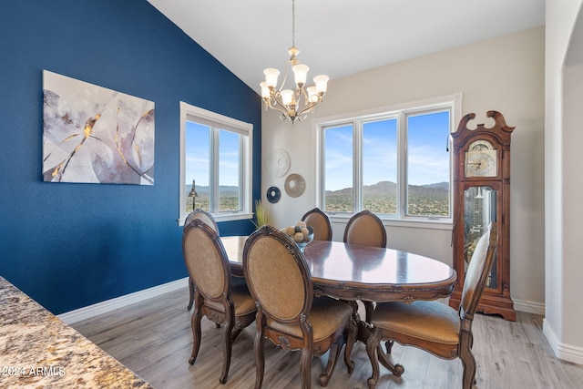 dining space featuring light wood-type flooring, lofted ceiling, a chandelier, and a mountain view