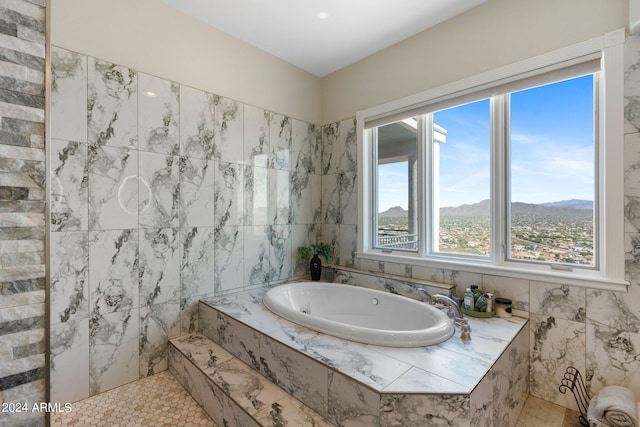 bathroom featuring tile walls, tile patterned floors, a mountain view, and a relaxing tiled tub