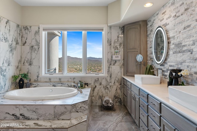 bathroom featuring tile walls, a mountain view, tiled bath, and vanity