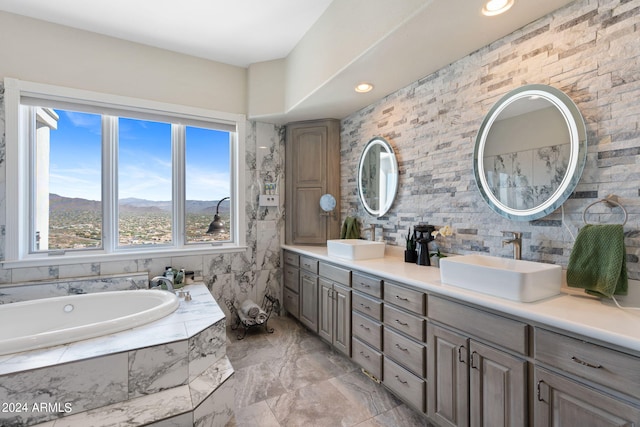 bathroom with tile walls, a mountain view, tiled tub, and vanity