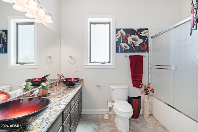 full bathroom with enclosed tub / shower combo, plenty of natural light, vanity, and toilet