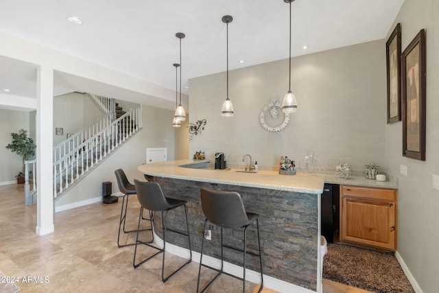 bar featuring sink, light stone counters, and decorative light fixtures