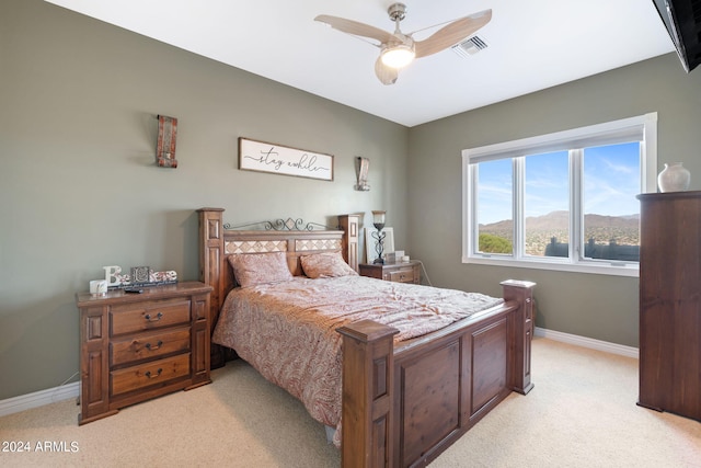 bedroom featuring a mountain view, ceiling fan, and light colored carpet