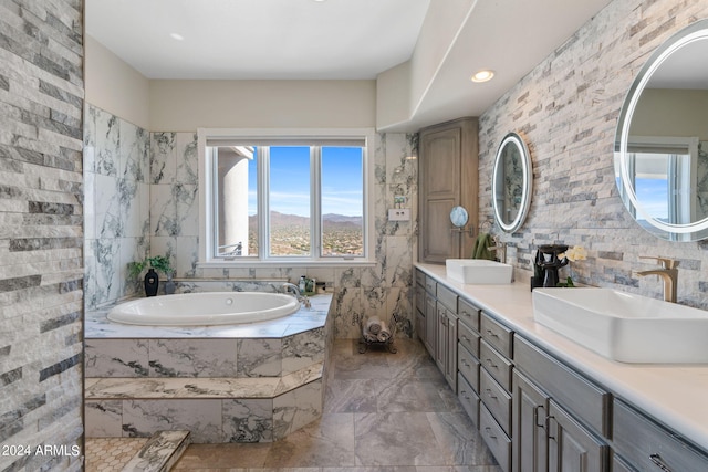 bathroom featuring tiled tub, vanity, and tile walls