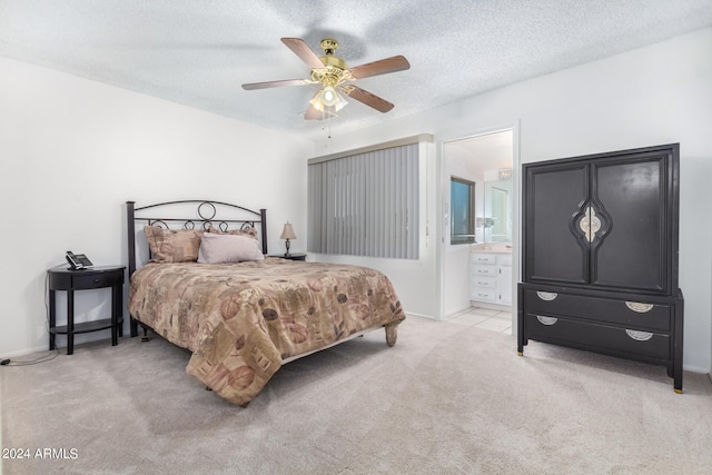 bedroom featuring a textured ceiling, light colored carpet, ensuite bath, and ceiling fan