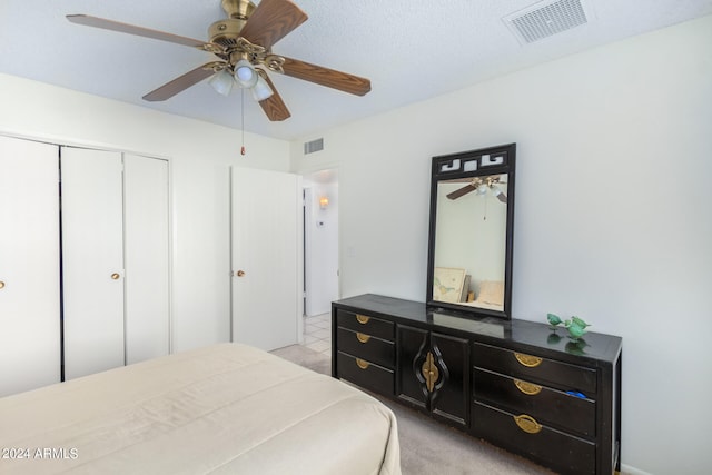 carpeted bedroom featuring ceiling fan, a closet, and a textured ceiling