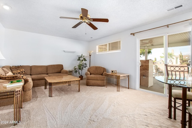 carpeted living room with ceiling fan and a textured ceiling