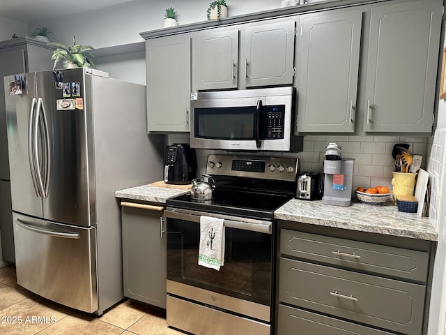 kitchen featuring light tile patterned floors, decorative backsplash, gray cabinetry, and stainless steel appliances