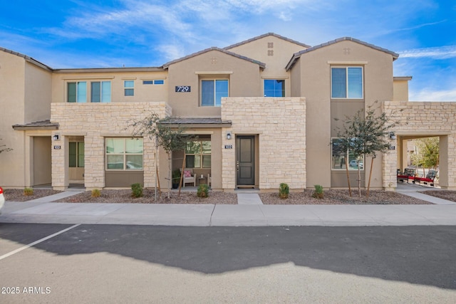 view of front of property featuring stone siding and stucco siding