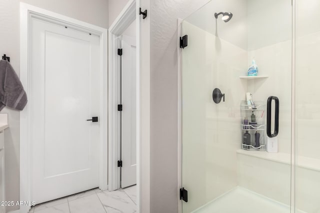 bathroom featuring marble finish floor and a stall shower