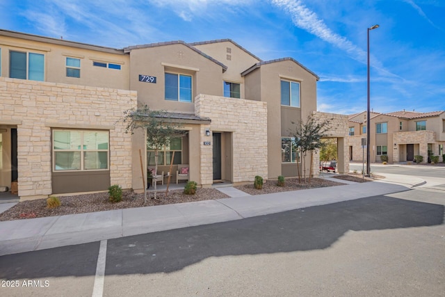 multi unit property with stone siding, a residential view, and stucco siding