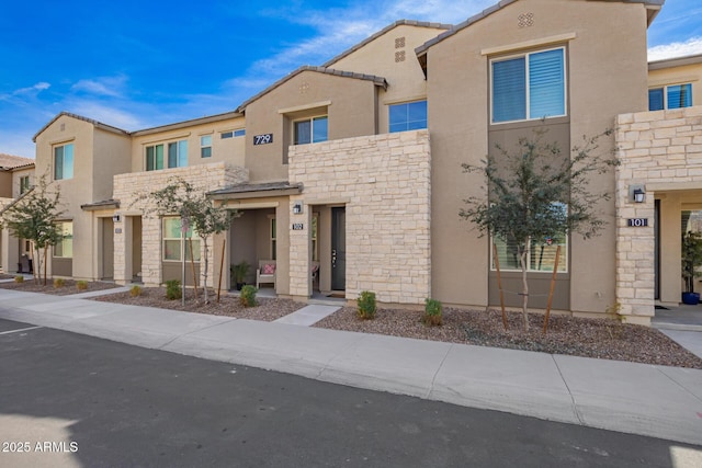 townhome / multi-family property featuring stone siding, a tiled roof, and stucco siding