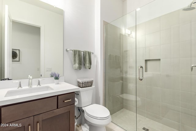 bathroom featuring vanity, a shower with shower door, and toilet