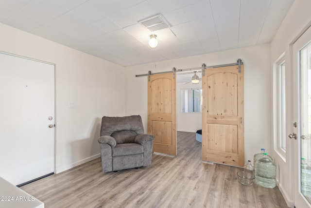 sitting room featuring a barn door, plenty of natural light, and light hardwood / wood-style floors