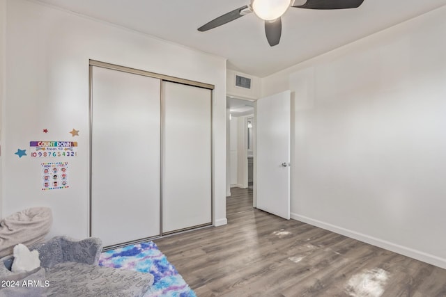 bedroom with ceiling fan, a closet, and hardwood / wood-style flooring