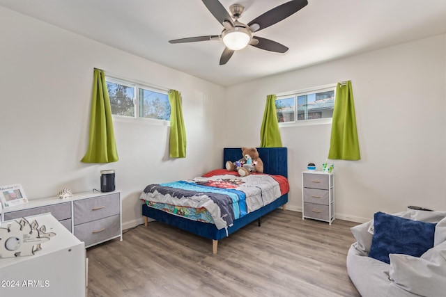 bedroom with hardwood / wood-style floors, ceiling fan, and multiple windows