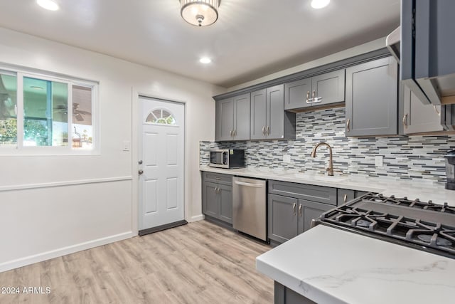 kitchen featuring appliances with stainless steel finishes, backsplash, sink, light hardwood / wood-style flooring, and gray cabinets