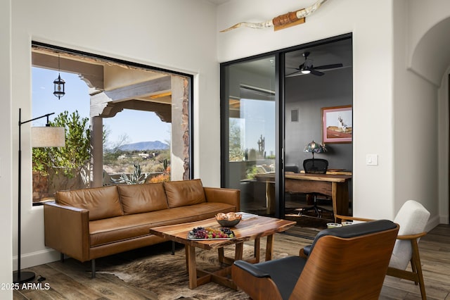 living room with a mountain view, baseboards, ceiling fan, and wood finished floors