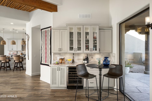 bar featuring visible vents, beam ceiling, beverage cooler, backsplash, and indoor wet bar