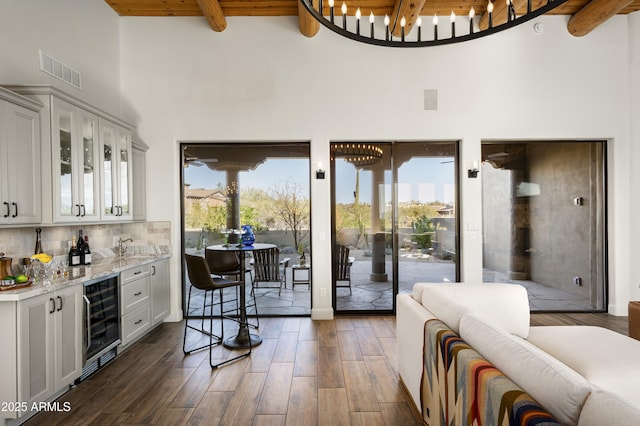 interior space with beverage cooler, visible vents, beamed ceiling, and dark wood-style flooring