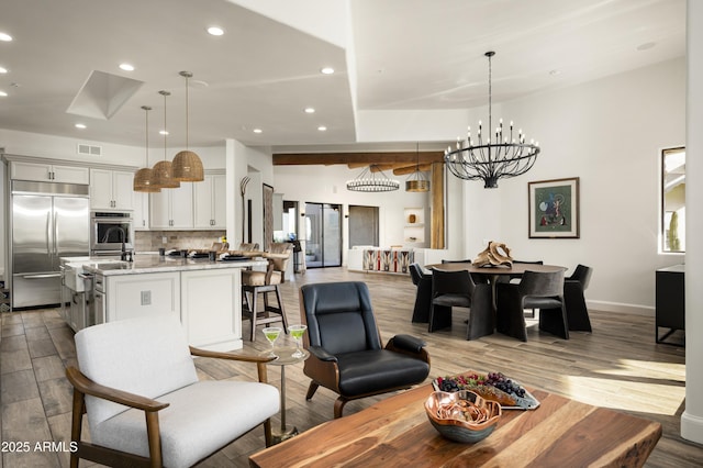 living room featuring baseboards, visible vents, light wood finished floors, recessed lighting, and a chandelier