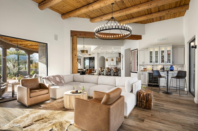 living area featuring visible vents, beam ceiling, dark wood finished floors, an inviting chandelier, and wooden ceiling