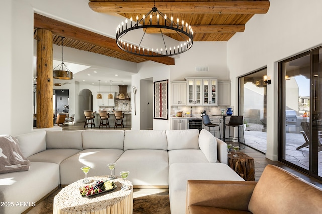 living room with visible vents, beamed ceiling, wood ceiling, arched walkways, and a notable chandelier