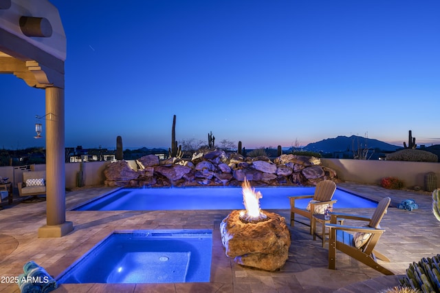 view of swimming pool featuring an in ground hot tub, a patio area, a fenced in pool, and an outdoor fire pit