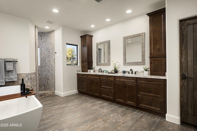 full bathroom with visible vents, wood finished floors, double vanity, tiled shower, and a soaking tub