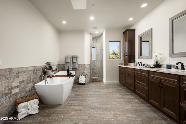 bathroom featuring a sink, recessed lighting, double vanity, tiled shower, and a freestanding bath