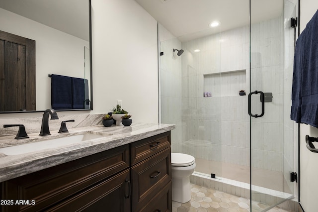 bathroom featuring toilet, a stall shower, vanity, and tile patterned flooring