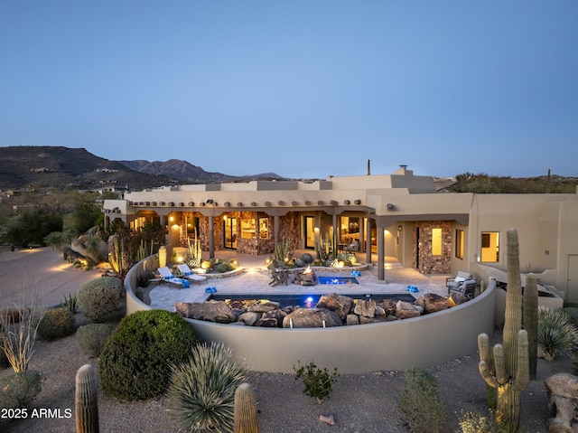 back of property featuring stucco siding, a patio, a mountain view, a fire pit, and an outdoor pool