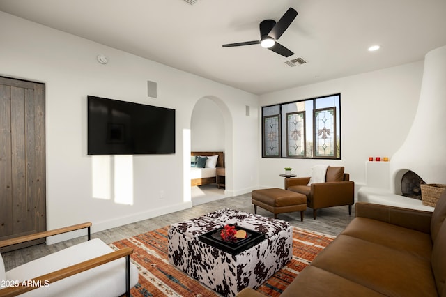 living room featuring visible vents, baseboards, wood finished floors, arched walkways, and a ceiling fan