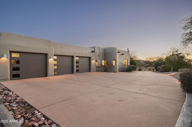 view of front facade with an attached garage, driveway, and stucco siding