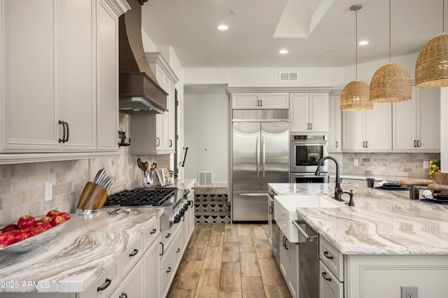 kitchen featuring a sink, custom range hood, visible vents, and stainless steel appliances