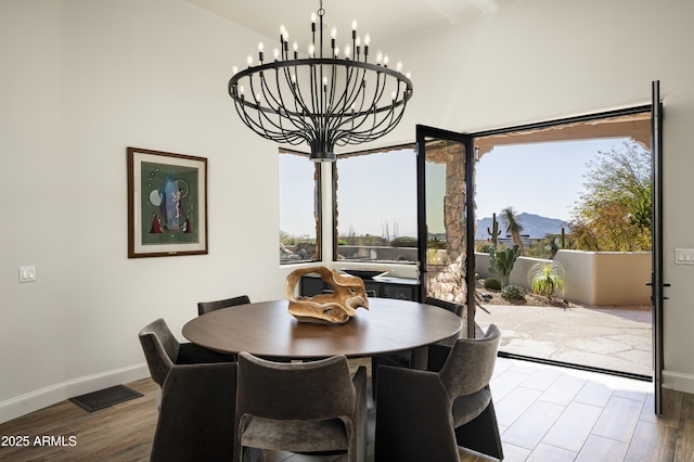 dining space featuring visible vents, baseboards, a notable chandelier, and wood finished floors