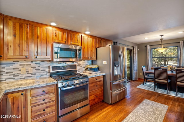 kitchen with brown cabinetry, appliances with stainless steel finishes, and hardwood / wood-style floors