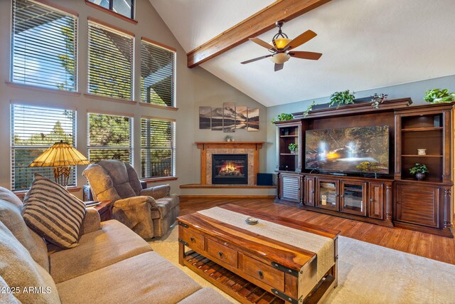 living room with beam ceiling, a tile fireplace, wood finished floors, high vaulted ceiling, and a ceiling fan