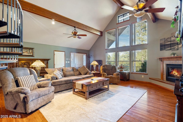 living room with beam ceiling, wood finished floors, baseboards, ceiling fan, and a tile fireplace