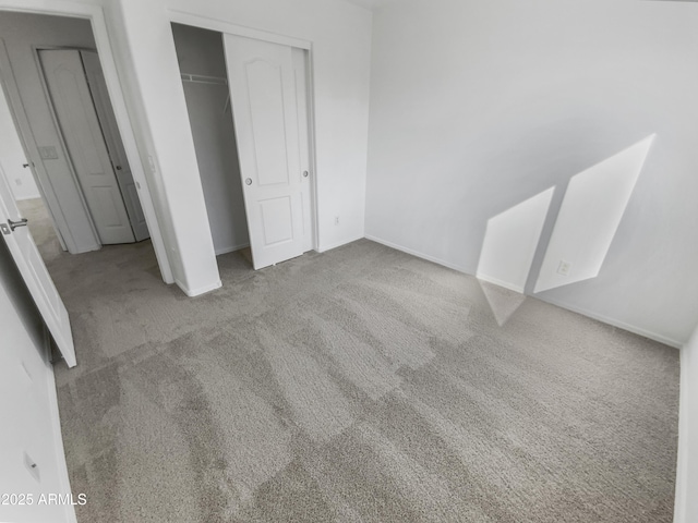 unfurnished bedroom with light colored carpet and a closet