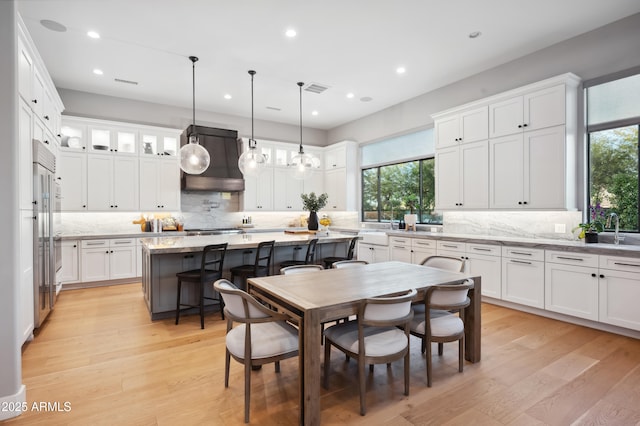 kitchen with decorative light fixtures, a center island, light hardwood / wood-style flooring, and white cabinets