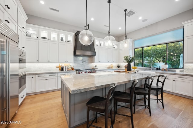 kitchen with premium range hood, a kitchen island, and white cabinets