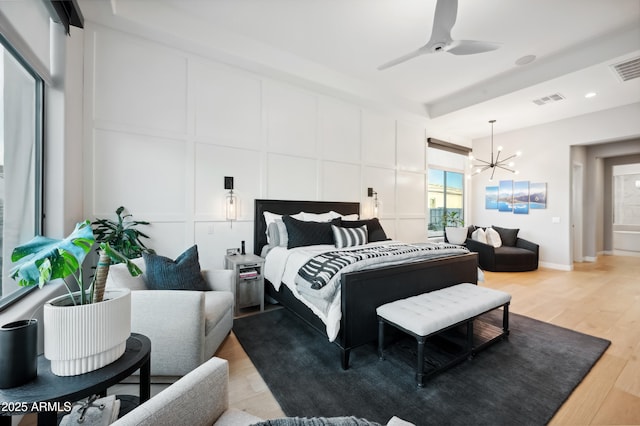 bedroom featuring ceiling fan with notable chandelier and light wood-type flooring