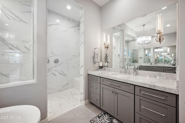 bathroom with an inviting chandelier, tiled shower, and vanity