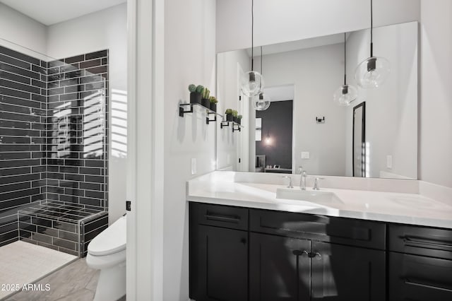 bathroom featuring vanity, toilet, and a tile shower