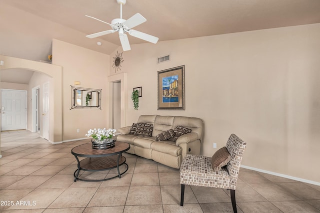 living room featuring a ceiling fan, visible vents, light tile patterned flooring, arched walkways, and vaulted ceiling