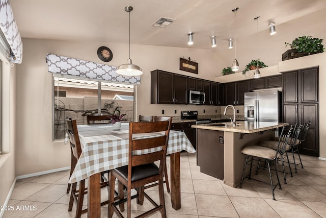 kitchen with a kitchen bar, visible vents, pendant lighting, stainless steel appliances, and light stone countertops