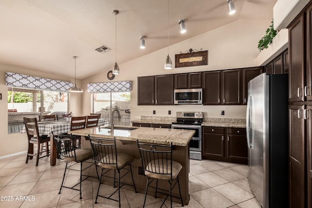 kitchen featuring visible vents, a sink, stainless steel appliances, light tile patterned floors, and dark brown cabinets