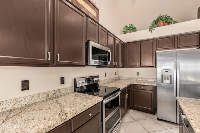 kitchen with dark brown cabinetry, light tile patterned floors, and stainless steel appliances